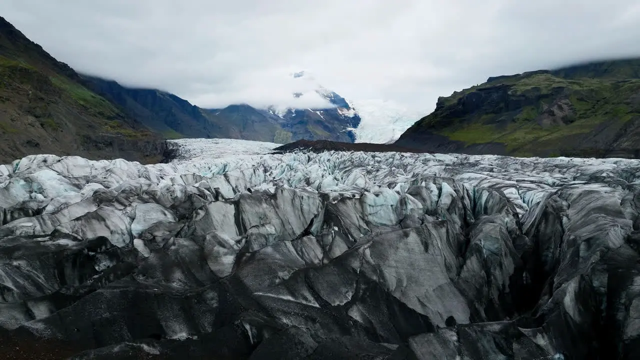 Icelandic landscape of a glacier tongue spurting off ice cap drone shot