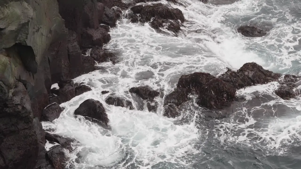 North Atlantic ocean waves hit against volcanic stone cliff Iceland