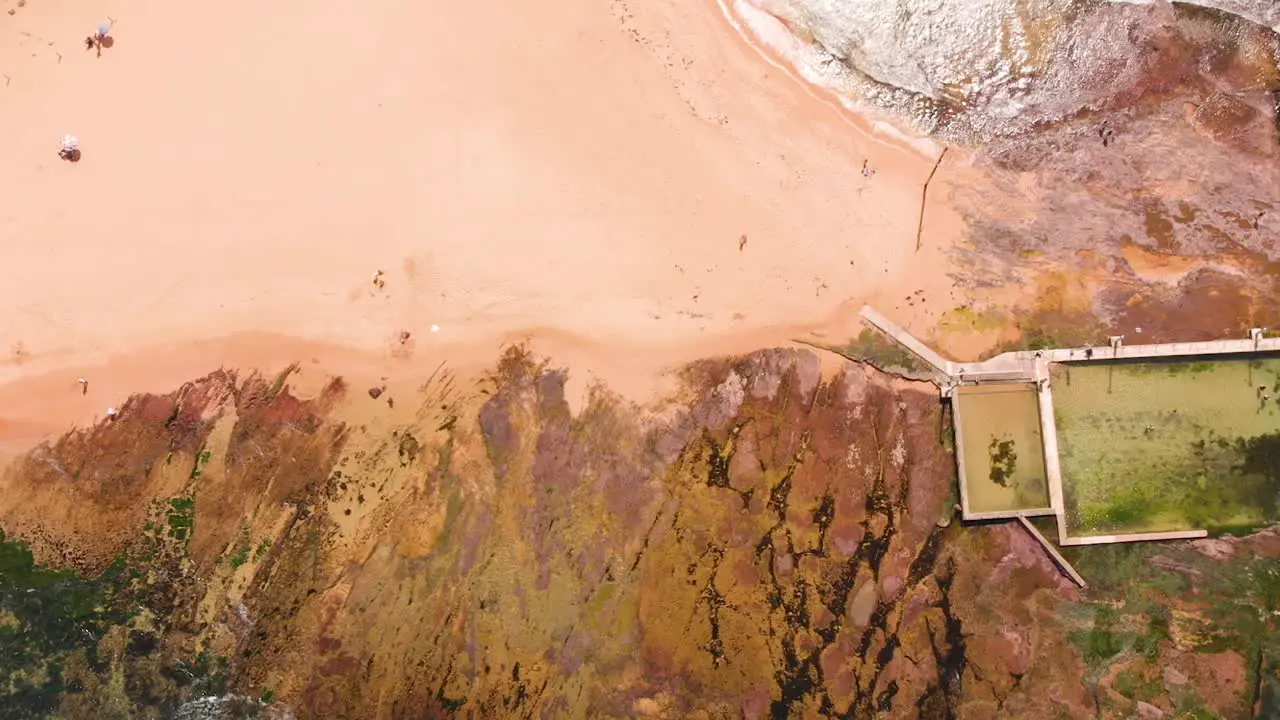 Cinematic top down drone aerial view slowly moving across a rock pool alongside the beach in Sydney Australia