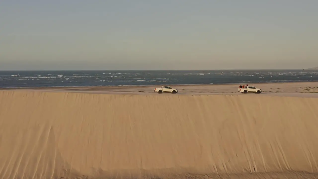 Offroad trucks explore coastal Brazil desert dune top in sunset