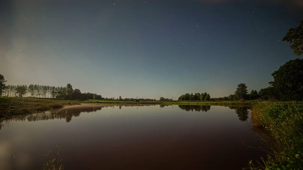 Time lapse shot of bright shining moon lighting on natural lake in nature