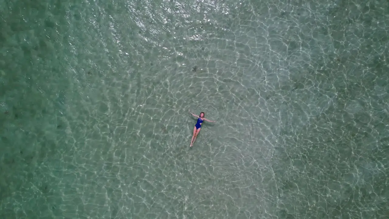 woman in blue swimsuit floating in crystal clear