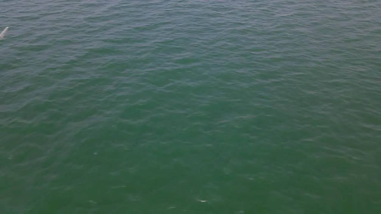 Aerial footage over a fishing boat in the middle of the ocean sliding to the right in Chonburi Thailand