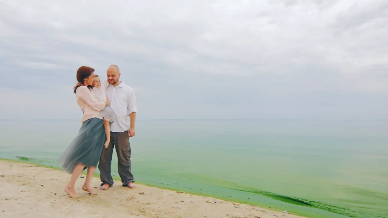 Young Family Of Three Posing For A Photograph On Beach