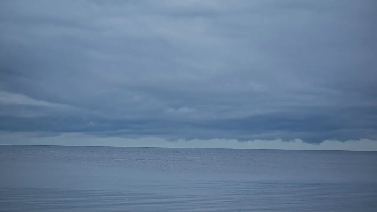  Timelapse shot of movement of thick clouds over blue sea water along shoreline at daytime