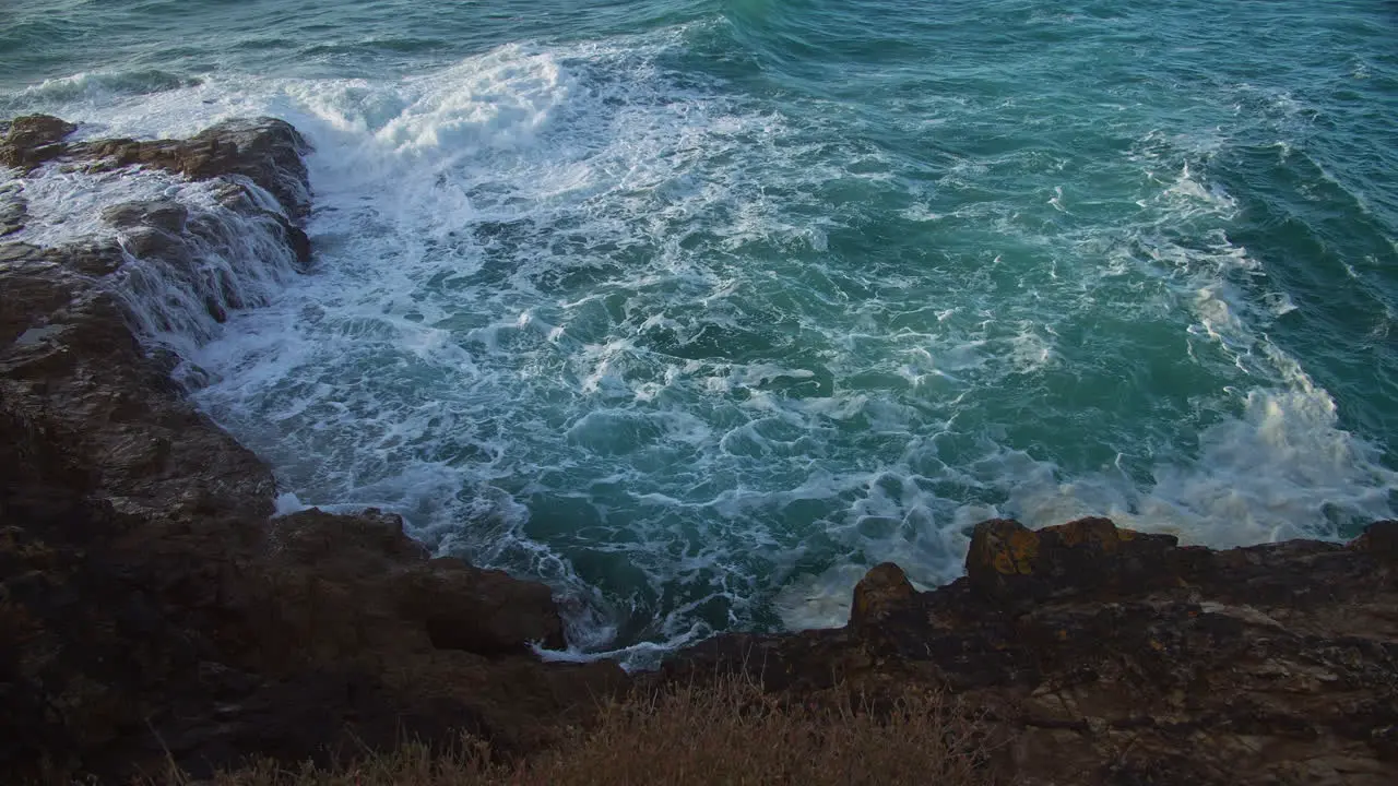 Turquoise Blue Waves Crashing Rocky Shoreline In Perranporth Cornwall static shot