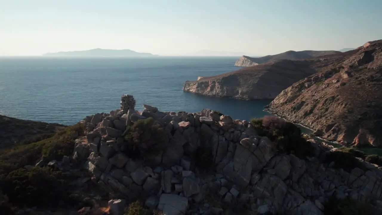 Drone rises above cairn at summit to reveal stunning vast ocean expanse from syros greece island