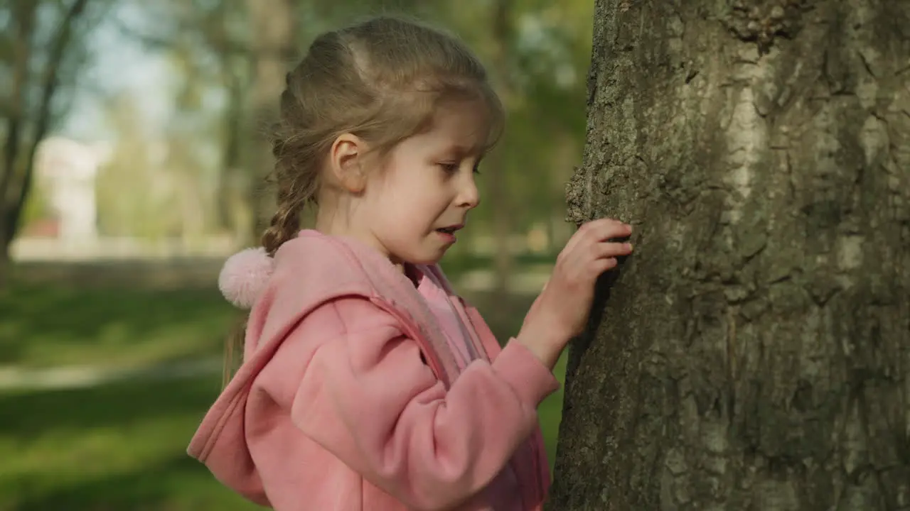 Disgusted little girl looks at bugs on tree in spring park