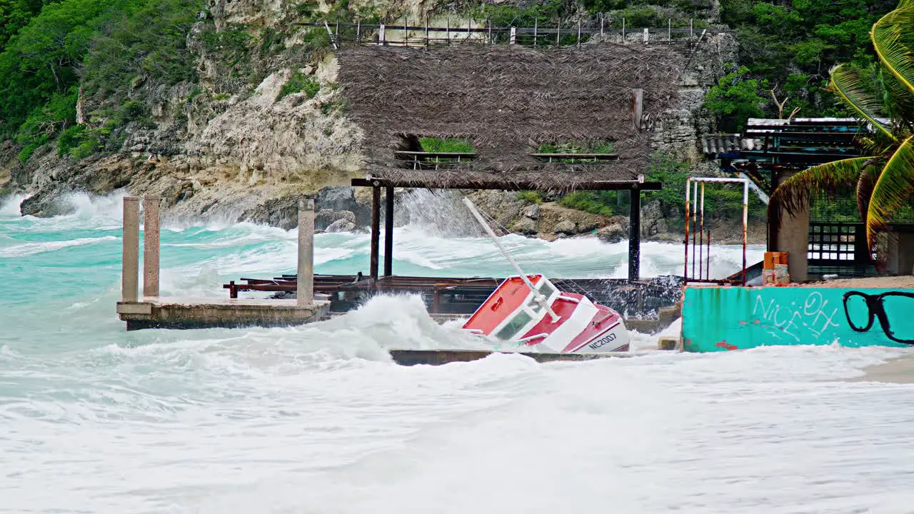 Local wooden fishing boat being smashed to pieces on land during sudden storm with rough waves Caribbean