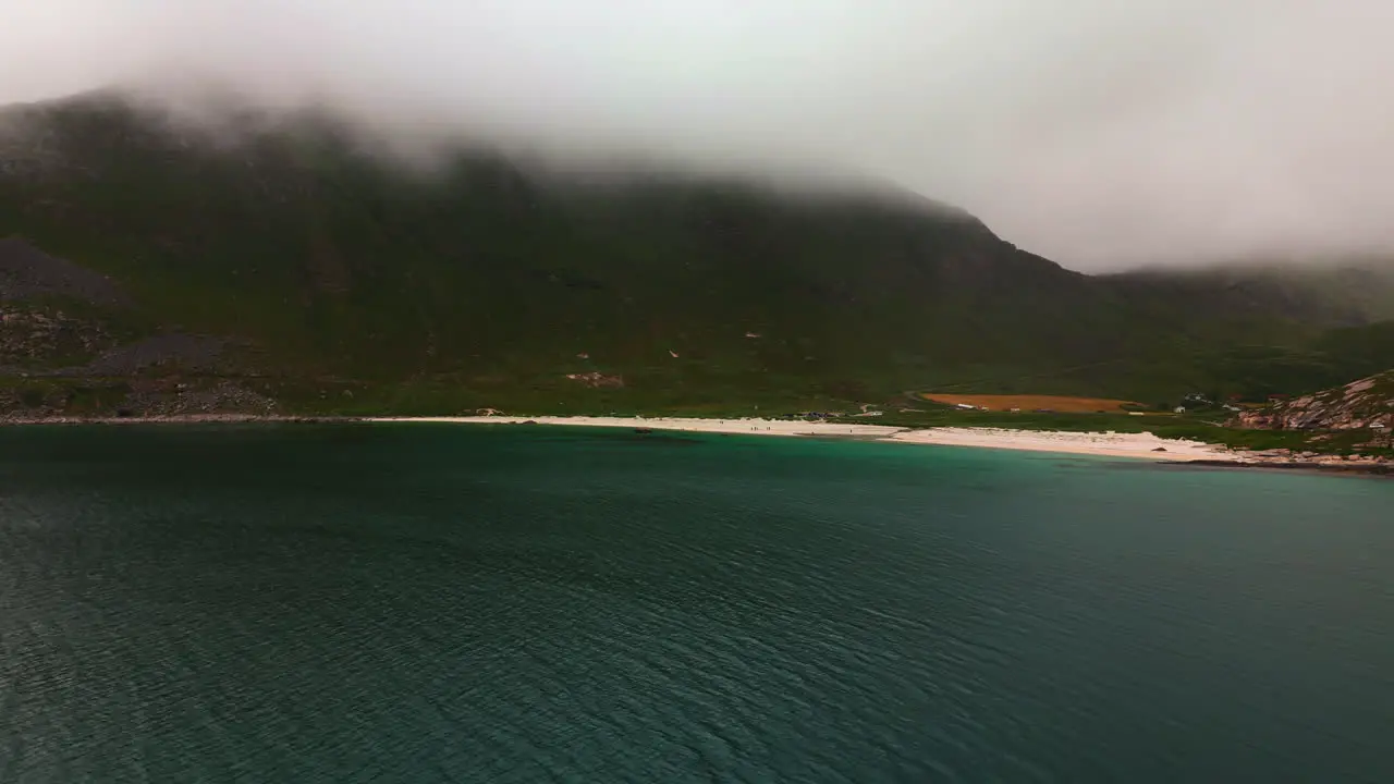 Cinematic aerial shot of the famous Haukland beach in the lofoten islands in the arctic north on a cloudy and foggy summer day with green water Drone