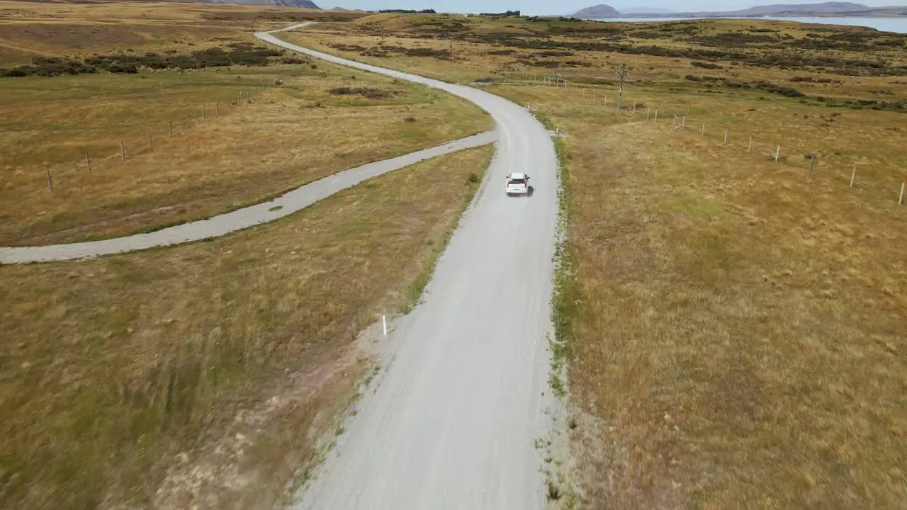 Fast white car on scenic dirt road within dry plains