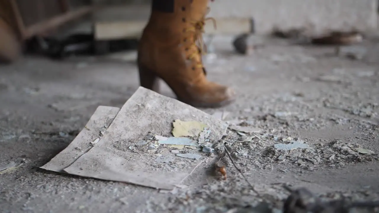 A close up shot a woman with a pair of suede brown boots kicking a pile of dust and trash aggressively