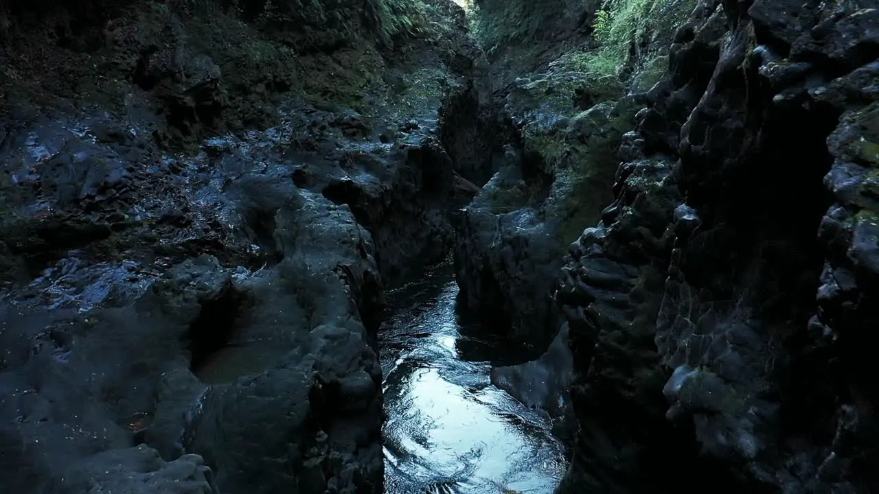 Aerial flying through tight canyon with rocky walls and water flowing gently