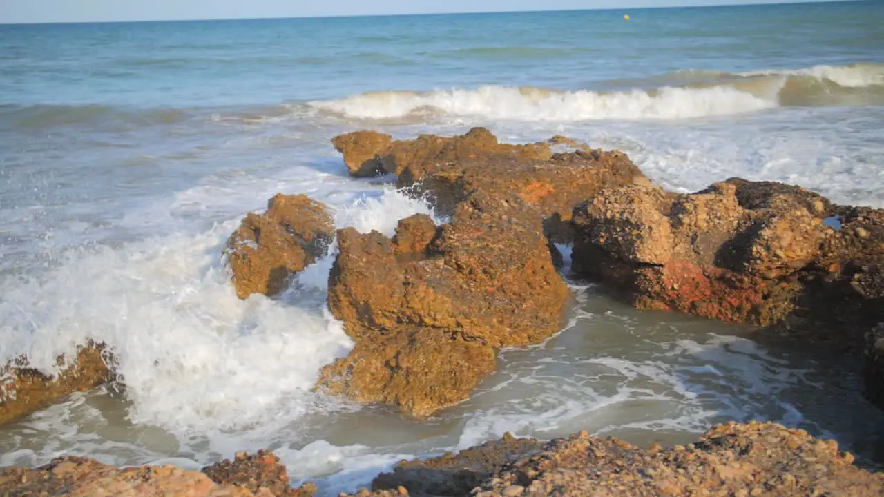 Waves crashing on rocks at coastal sea shore slow motion