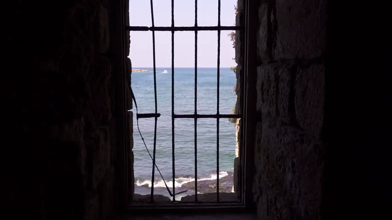 Abandoned building with latticed broken window over wavy sea