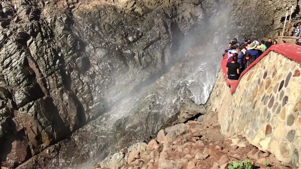 Tourists watching waves crashing on the rocks in a cliff at punta cometa