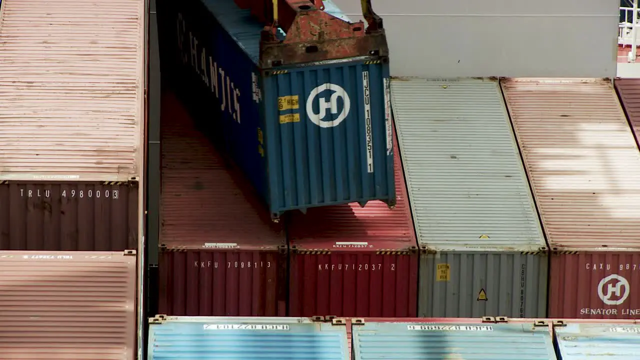 Harbor crane loads blue container to a cargo ship for export static telephoto