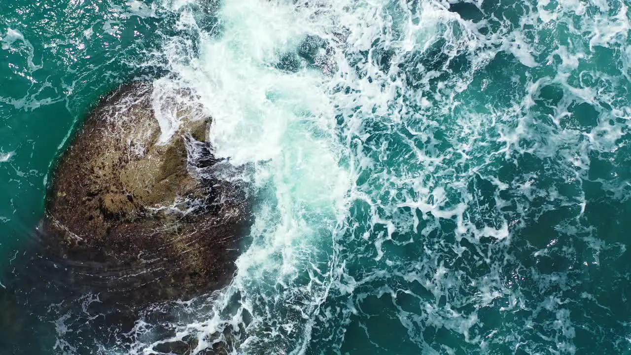 Foamy waves washing the big stone in the emerald ocean