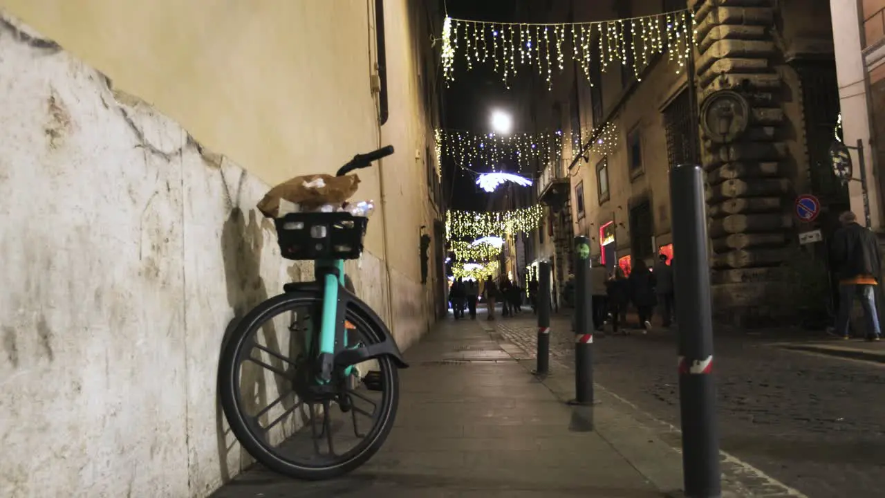 Street in Rome Italy at night with bicycle and pedestrians with an establishing shot