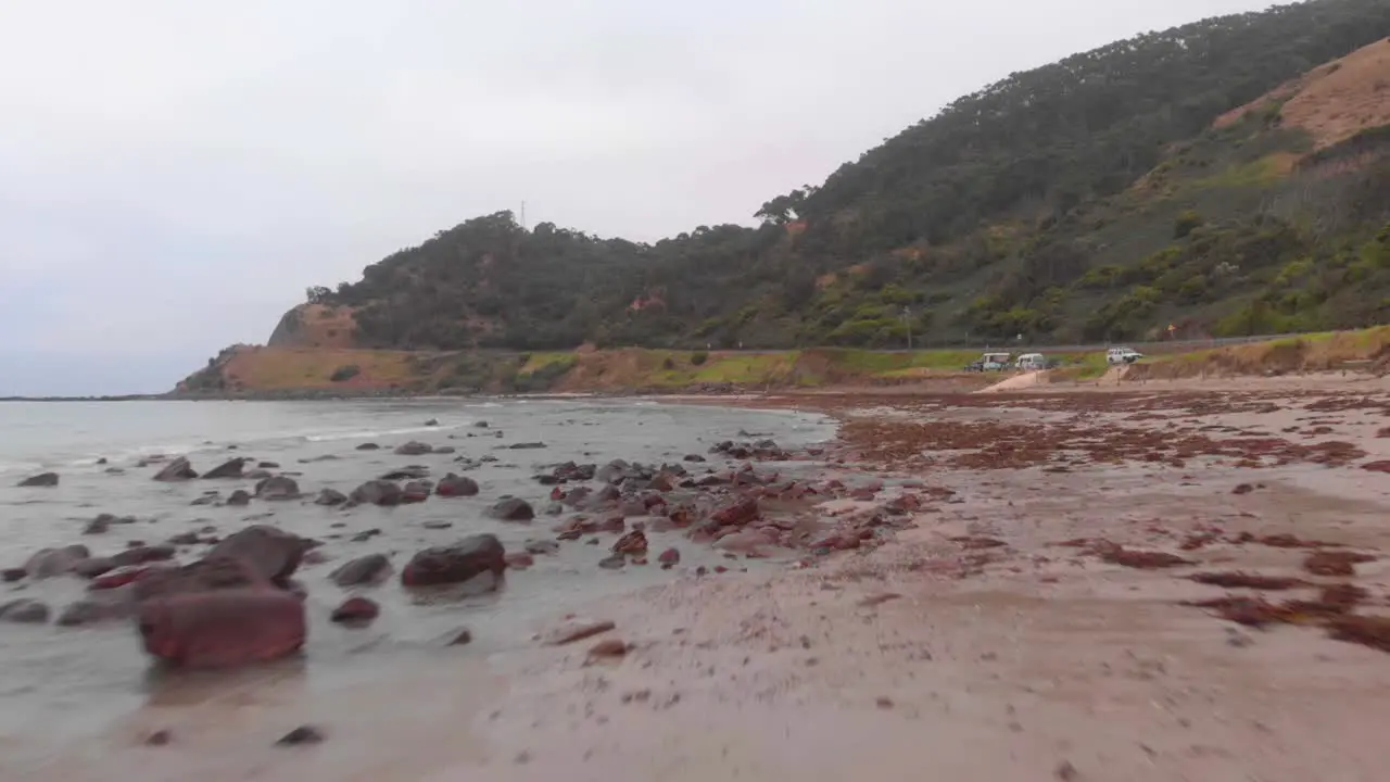 Low flying aerial drone over rocky wet beach on misty morining