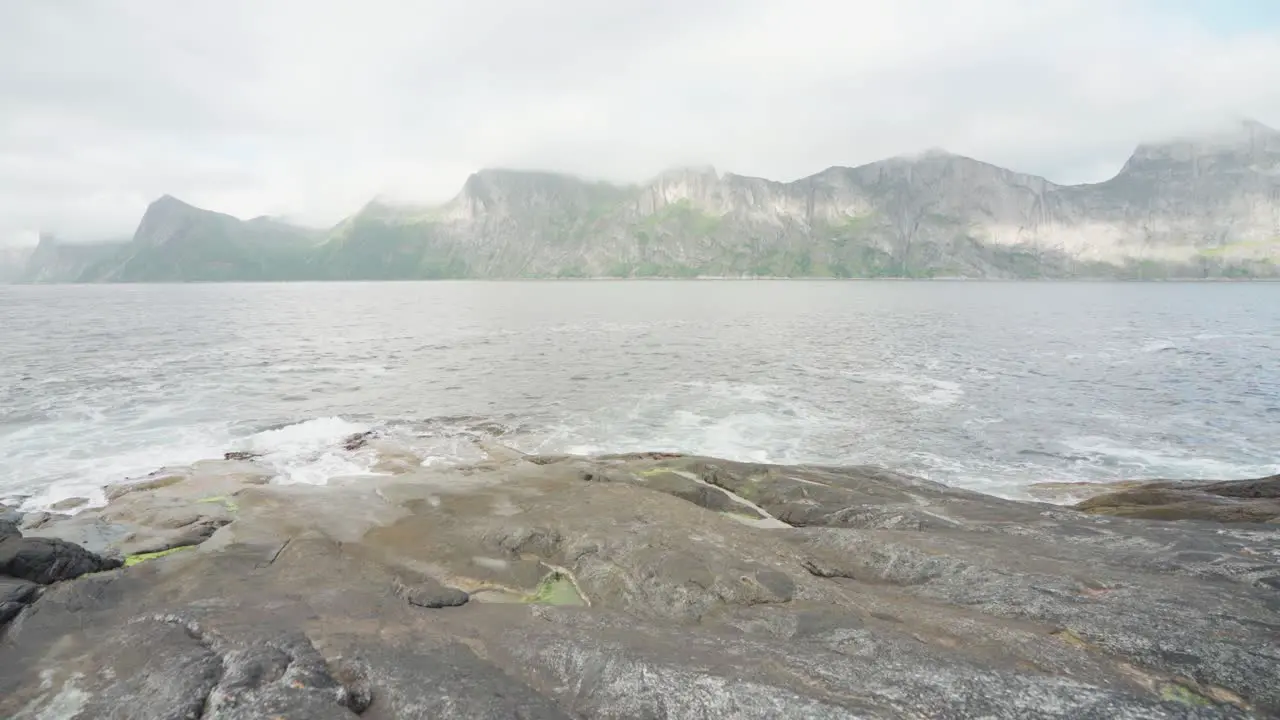 Hiker Fishing On The Shore Of The Sea In Anderdalen National Park In Senja Island Segla Norway With Mountains In The Background