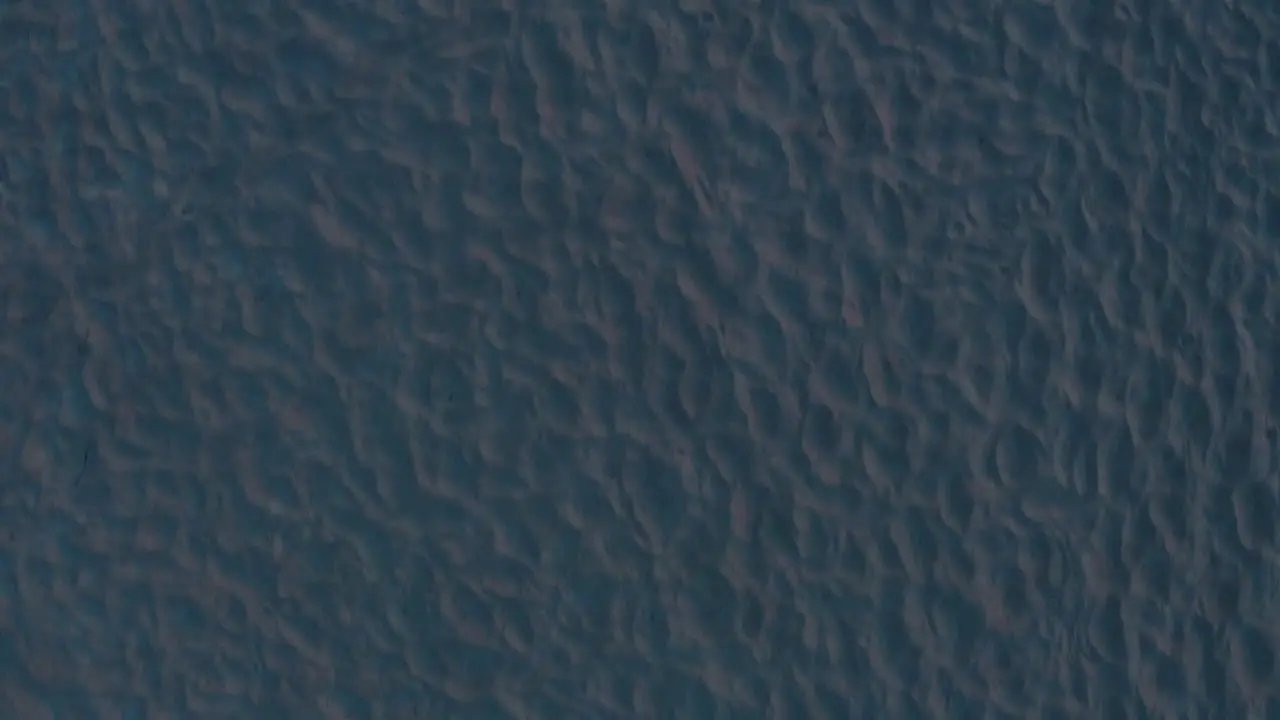 4k Top down aerial shot of abstract white sand on a beach during sunet