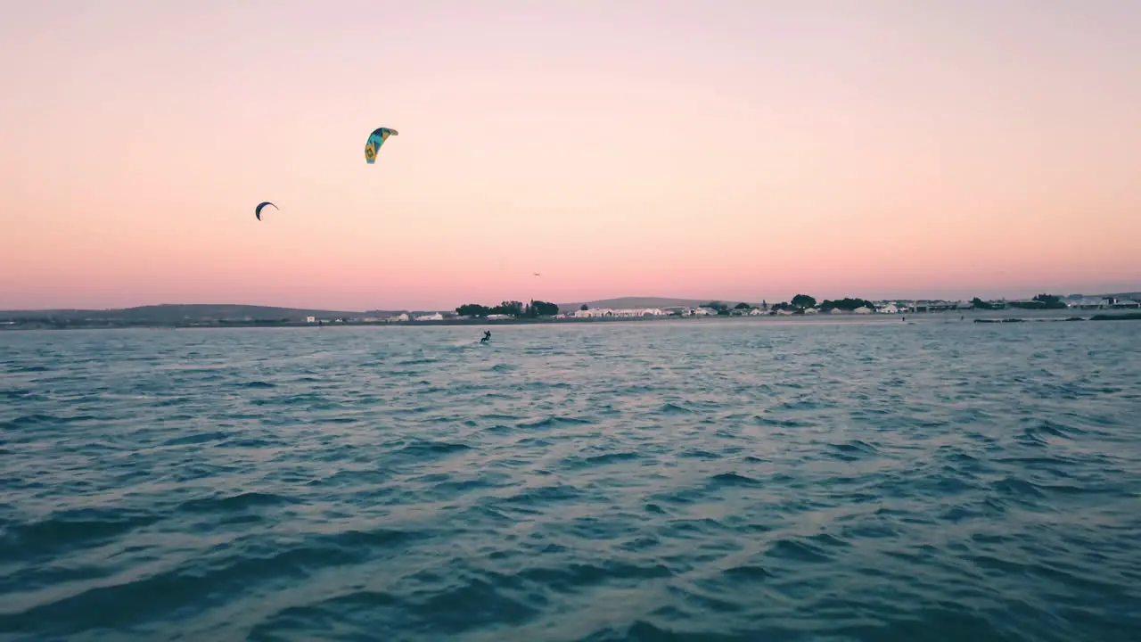 ultra wide drone shot following kite surfers on scenic sunset on Langebaan Beach Cape Town South africa with summer vacation silhouette