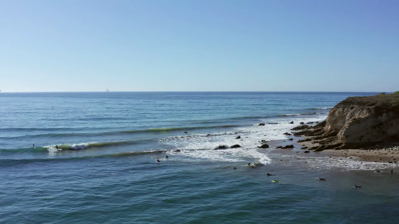 Aerial Distant surfers in gentle ocean waves of California coast