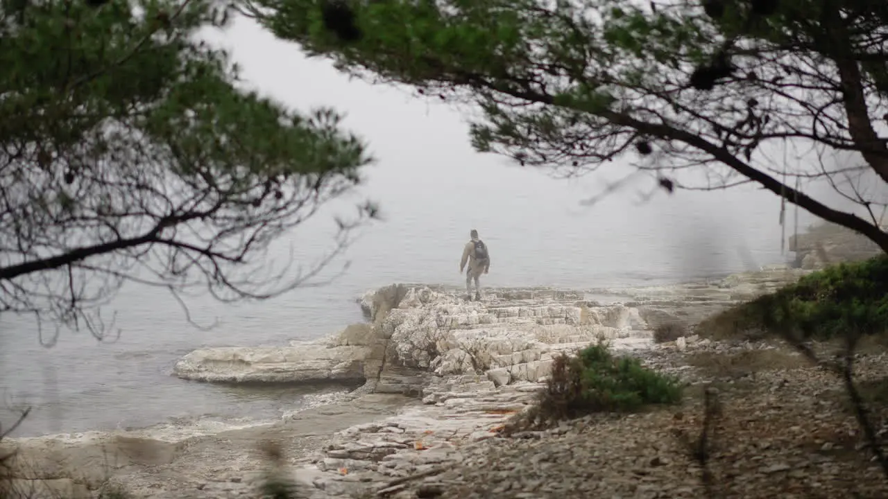 Young man jumping to the edge of rocky beach and looking into distance