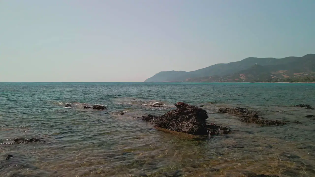 Flying Backwards On The Beautiful Transparent Water And Rocks Of Sardinia During A Sunny Day Of Summer In Italy aerial drone shot