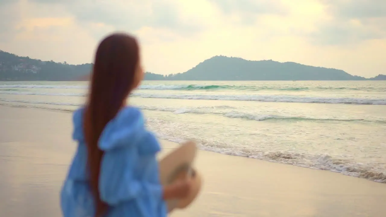 Woman Stepping in Frame on Secluded Beach Puts on Sun Hat