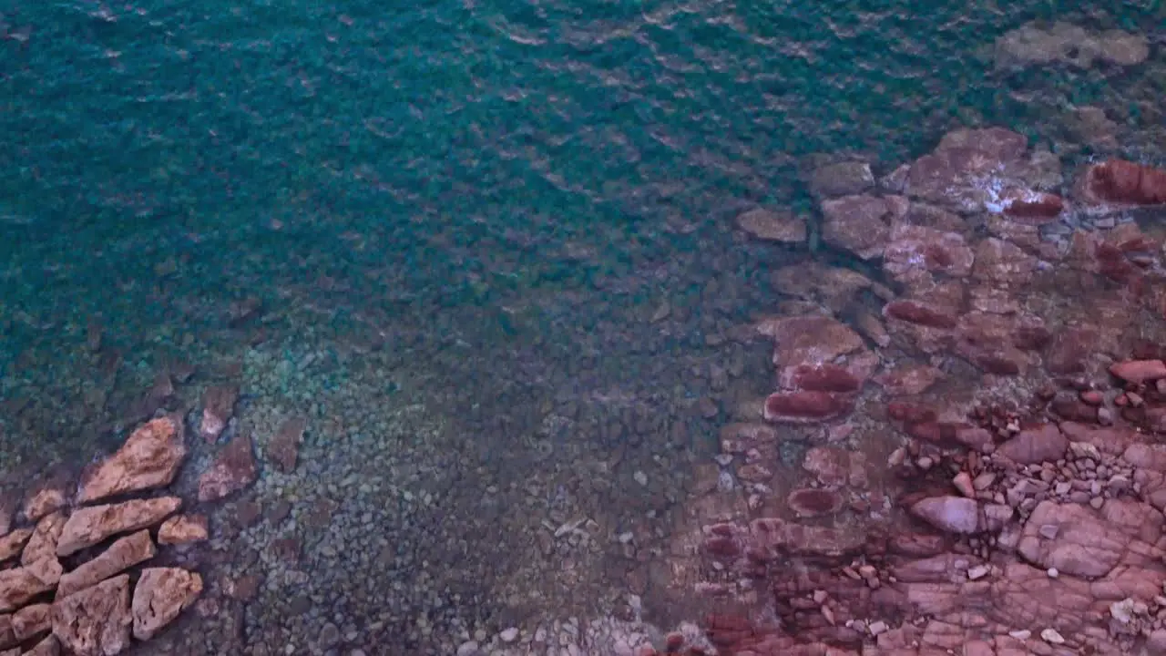 Overhead view of small paradisiac bay tilt reveals offshore lighthouse dusk