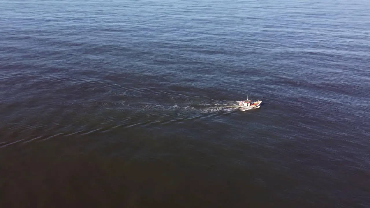 Backward drone flight over a fishing boat on the uruguayan coast in the atlantic ocean