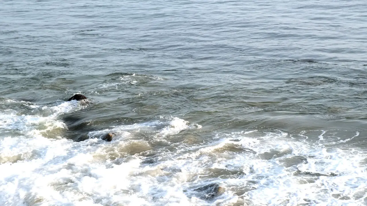 Waves hitting the rocky shoreline of Big Rock beach Malibu at golden magic hour time