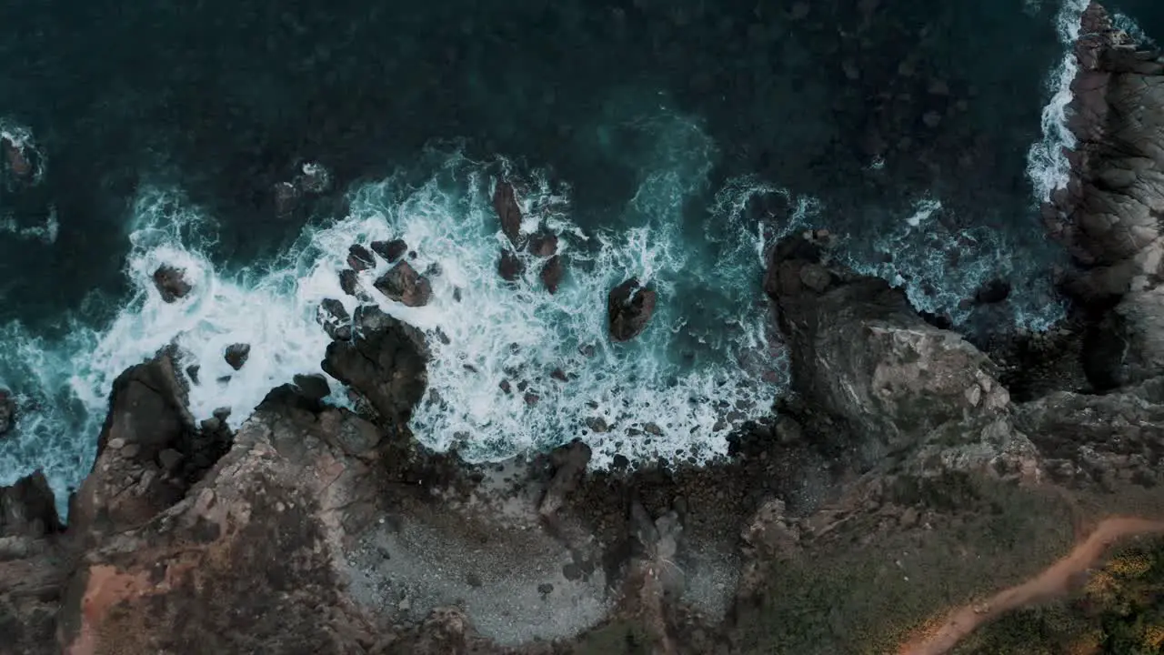 Ascend Top aerial drone view of waves crashing on rocky coastline