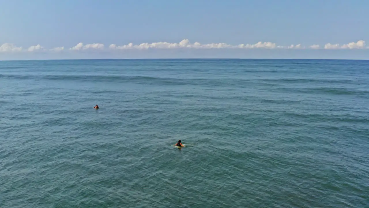 Aerial surfers sitting and relaxing on surfboards behind breaking waves