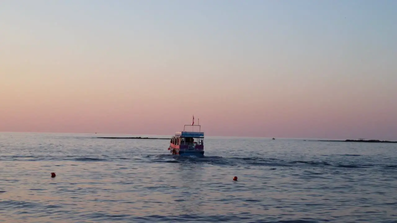 Picturesque view of calm ocean waters and boat traveling away from shore at sunset Tyre Lebanon pan left reveal