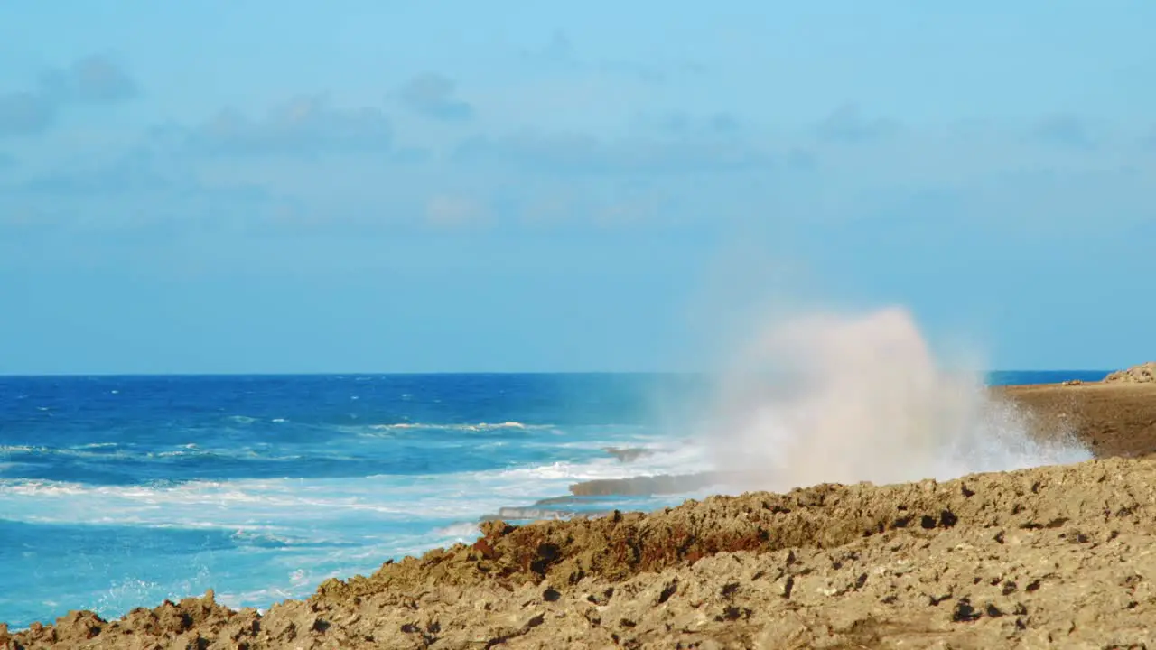 Waves crashing on coral coast and sending misty spray high into air