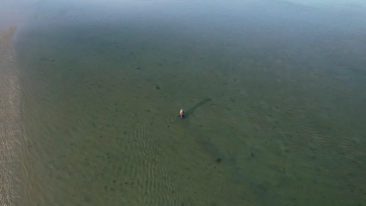 fisherman catching fish on shallow ocean sandbar at