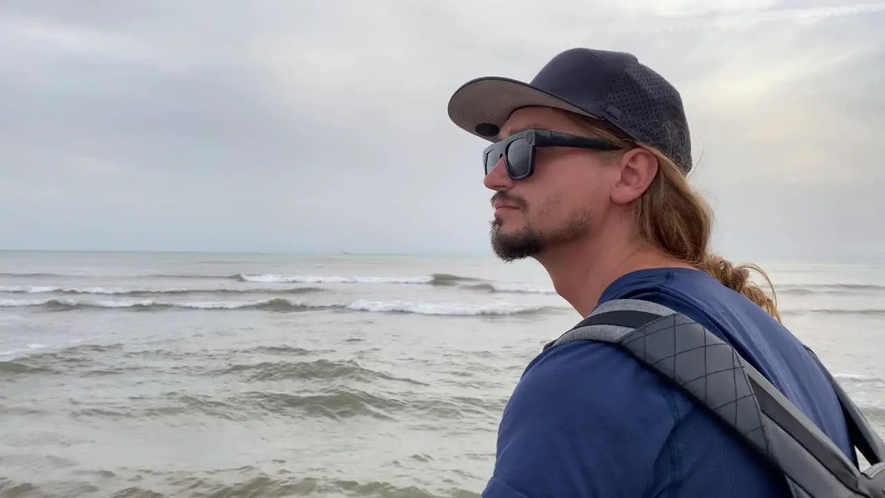 Man rotates head and looks out to sea in contemplation medium close up shot