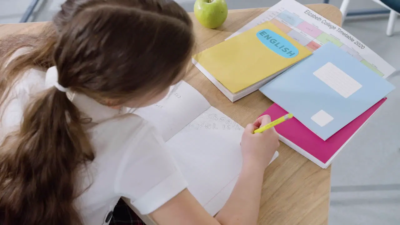 Niña Sentada En El Escritorio Y Escribiendo En Un Cuaderno Durante La Clase De Inglés En La Escuela