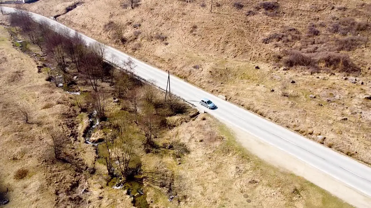 Drone footage of a car passing by on the road in the mountains in Romania